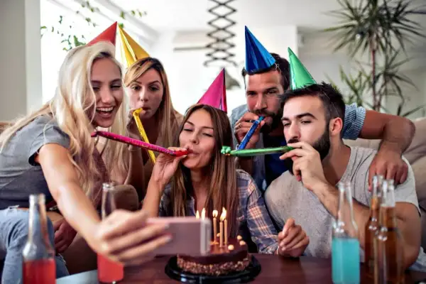 Grupa przyjaciół świętuje 30 urodziny, dmuchając w trąbki i robiąc sobie selfie. To świetne 30 urodziny inspiracje!